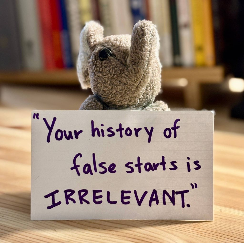 Paul holding an index card that reads: "Your history of false starts is IRRELEVANT."